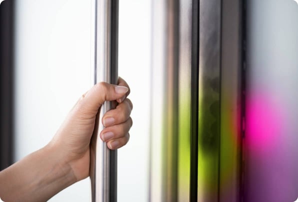 Close up of a hand gripping a vertical metal door handle