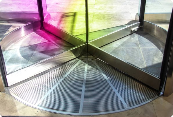 Glass revolving door, tinted with shades of purple and lime green that represent acre's brand colors